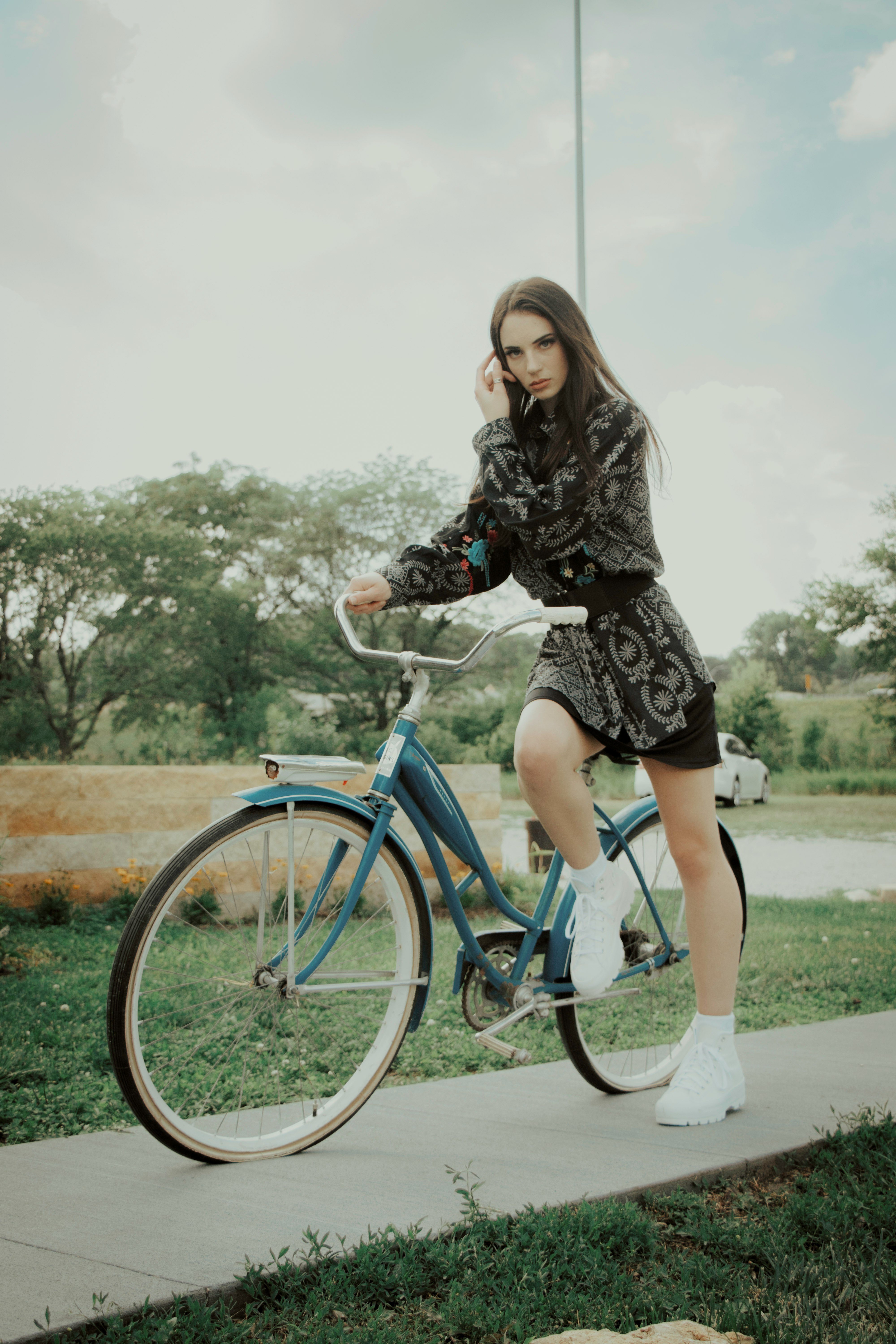 woman in black dress riding blue bicycle during daytime